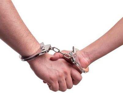 Man and woman holding hands in handcuffs